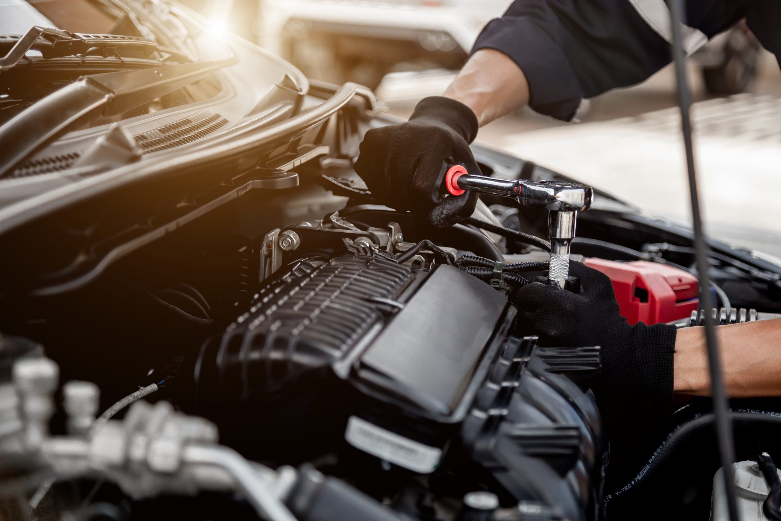 A mechanic is working on the engine of an automotive franchise.