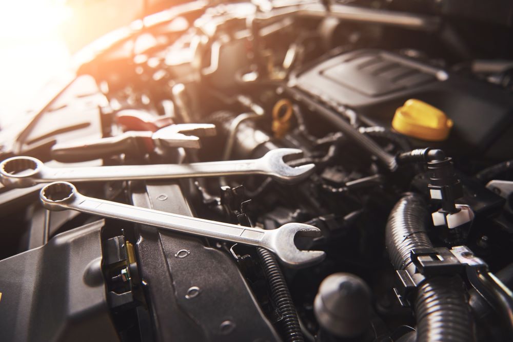 A close up of a car engine with a wrench on it.